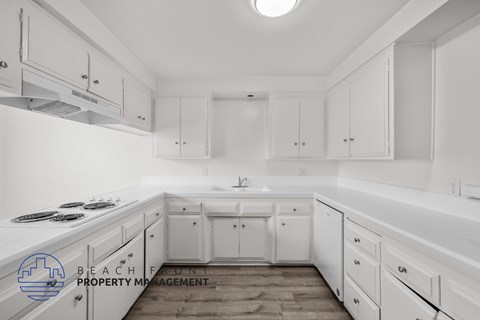 A kitchen with white cabinets and a stove top oven.