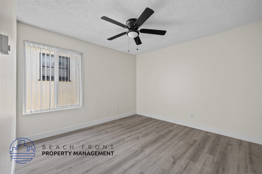 A room with a ceiling fan and wooden flooring.