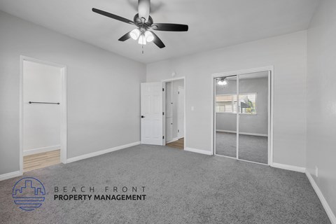 A spacious room with a ceiling fan and a logo for Beach Front Property Management.