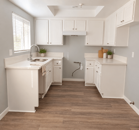 A kitchen with white cabinets and a wooden floor.