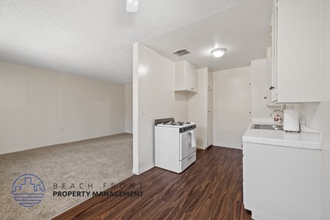 a kitchen with white appliances and white cabinets and wood flooring