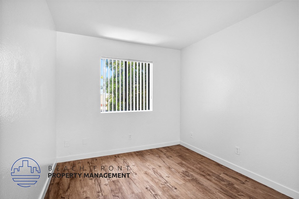 the living room of an apartment with wood flooring and a window