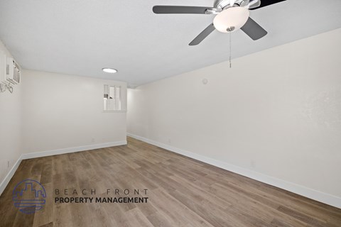 the living room of a house with white walls and a ceiling fan