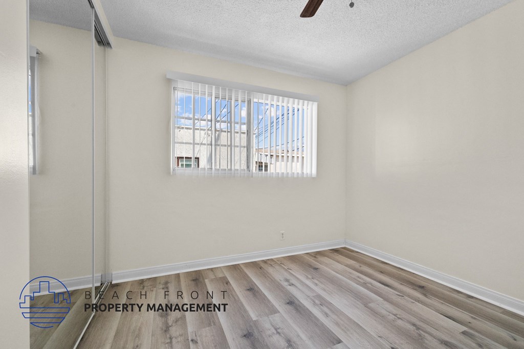 a bedroom with wood flooring and white walls and a window