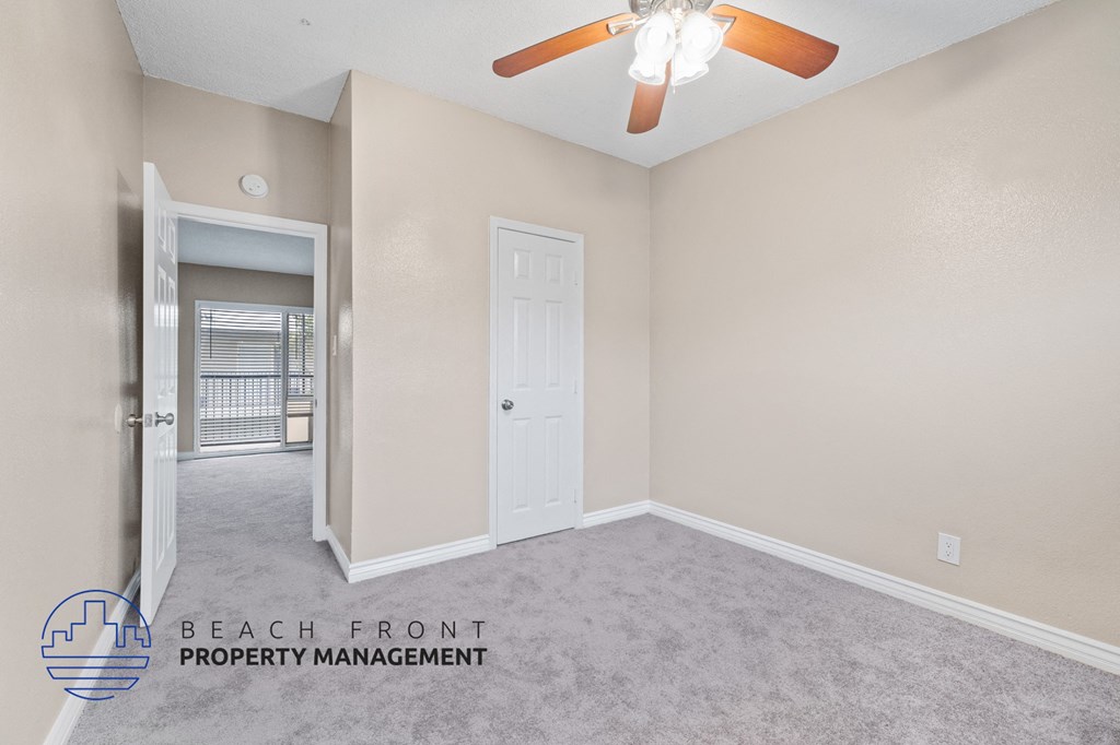 a bedroom with a ceiling fan and a door to the bathroom