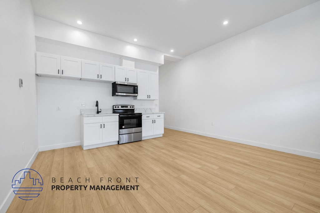 a living room with white walls and a kitchen with white cabinets