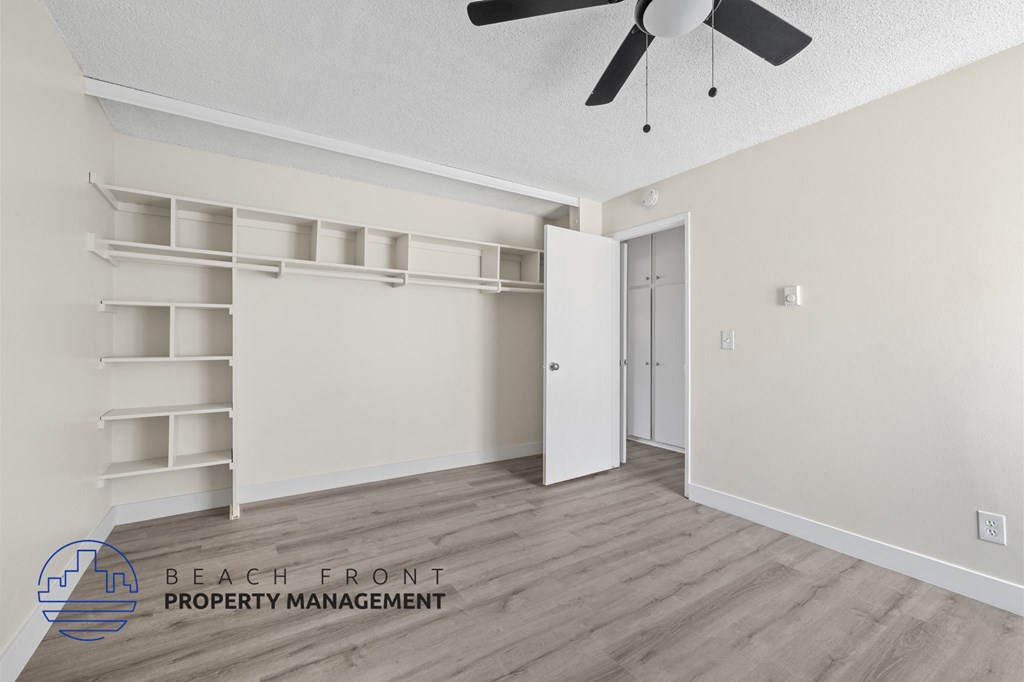A room with a ceiling fan and a door leading to another room.
