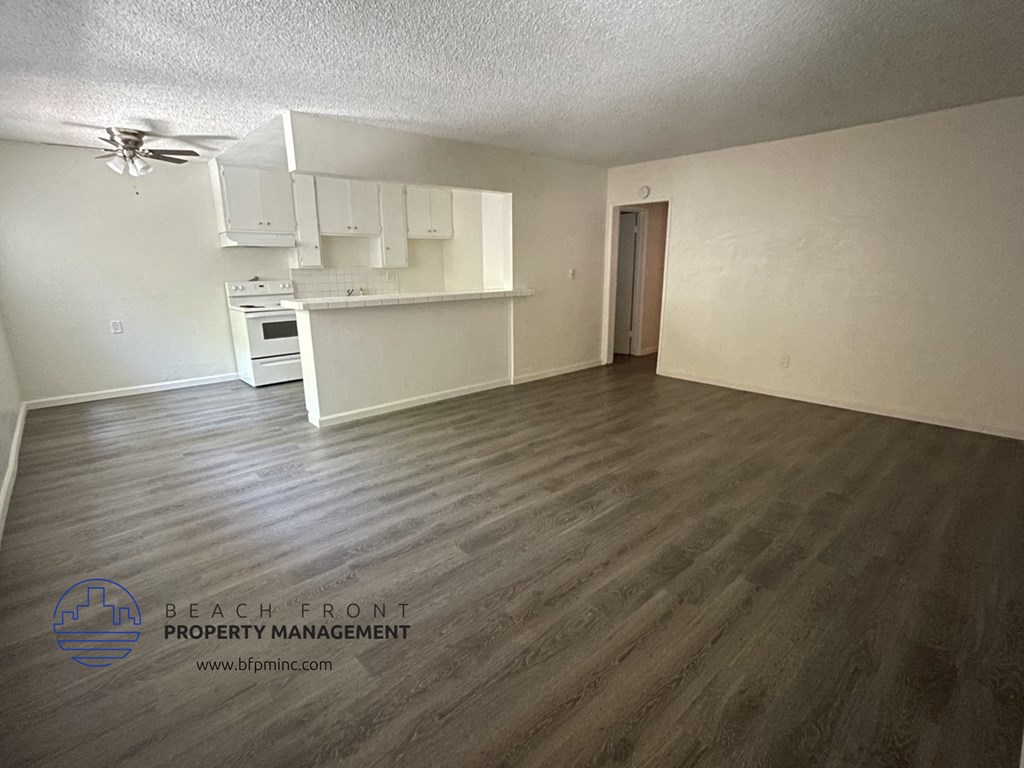 the living room and kitchen of an apartment with wood flooring