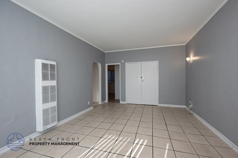 A spacious room with tiled flooring and white doors and windows.