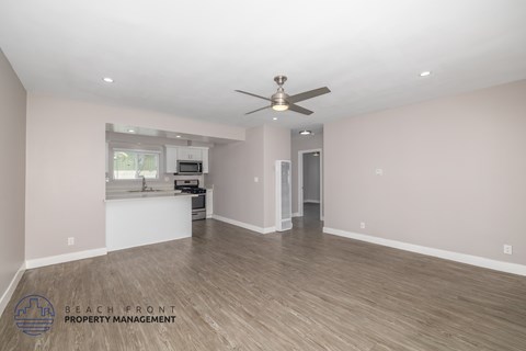 A spacious room with a ceiling fan and wooden flooring.