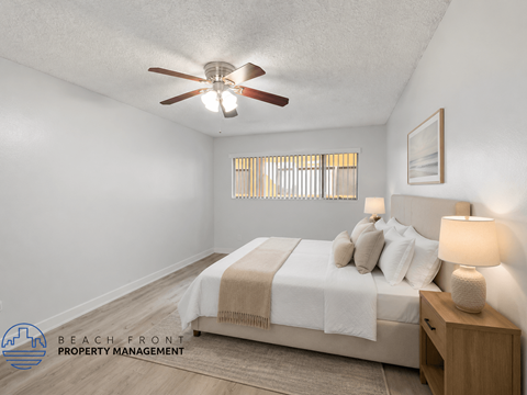 A bedroom with a bed, nightstand, and a ceiling fan.