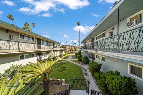 a row of apartments with balconies and a courtyard with palm trees