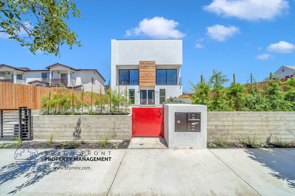 a white house with a red door and a fence