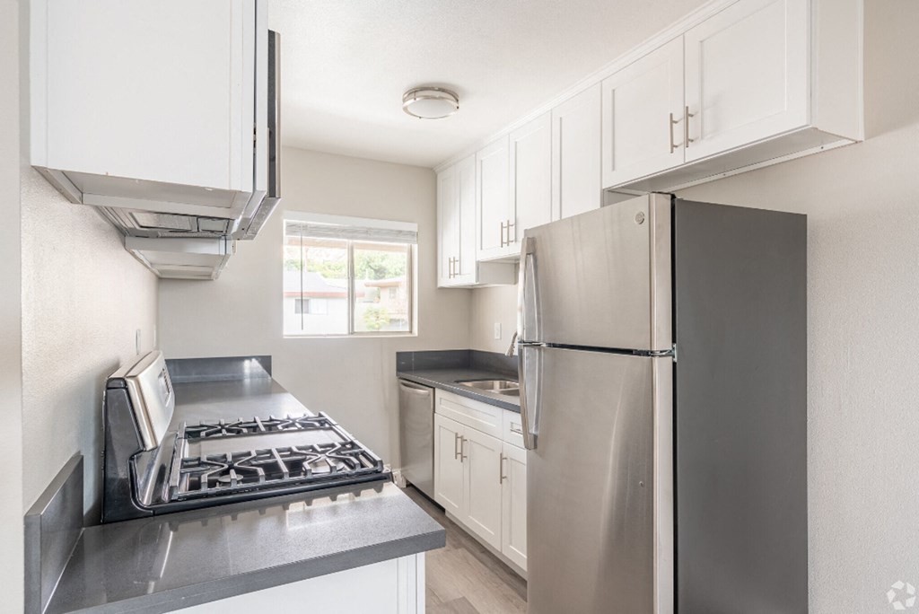 an empty kitchen with stainless steel appliances and white cabinets