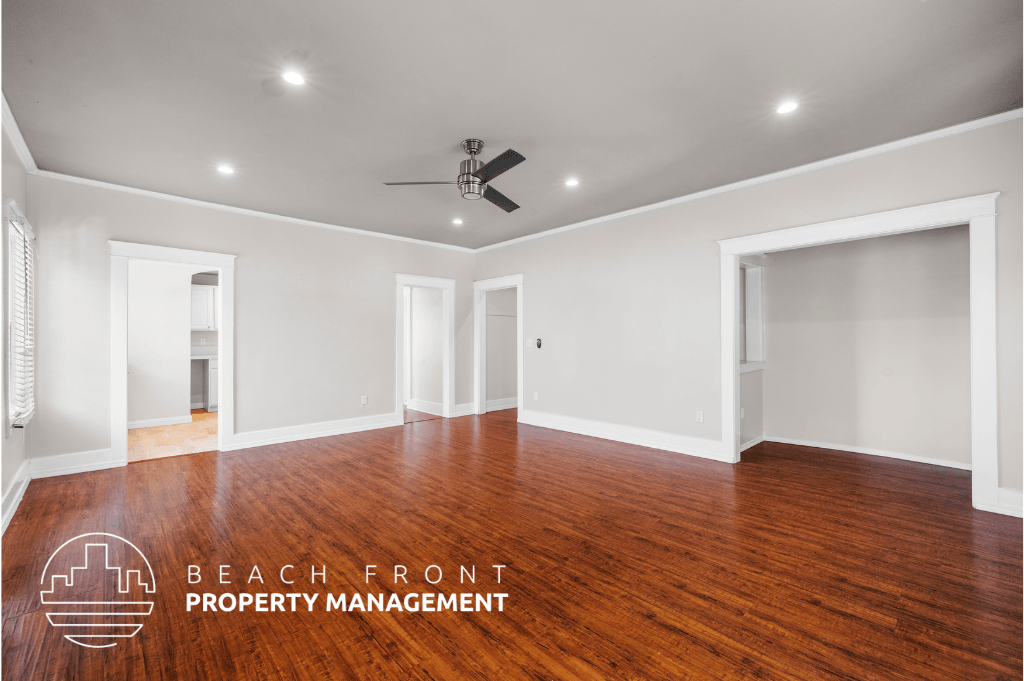 a living room with wood floors and white walls and a ceiling fan