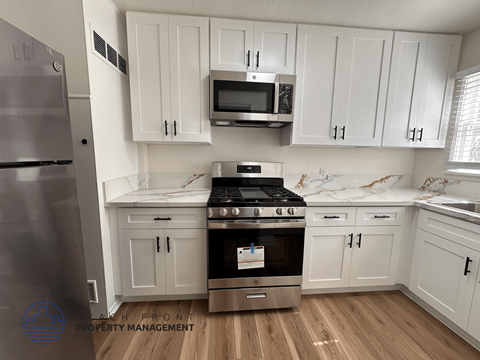 A kitchen with white cabinets and a stainless steel refrigerator.