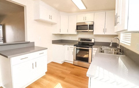 an empty kitchen with white cabinets and stainless steel appliances