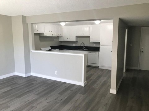 A kitchen with white cabinets and a grey floor.