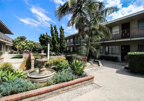 A courtyard with a fountain surrounded by plants and trees.