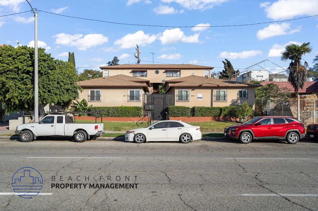 A white car is parked in front of a house with a sign that says Beachfront Property Management.