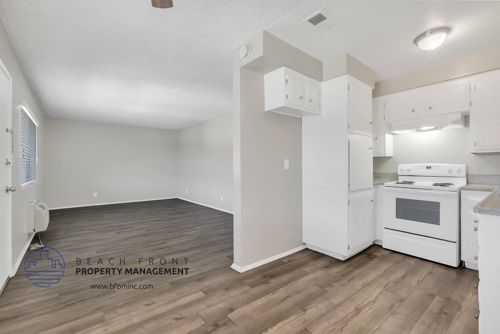 a white kitchen with white appliances and wood flooring