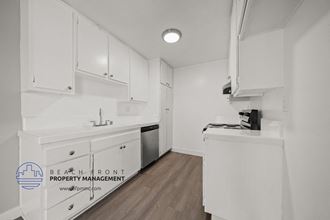 a white kitchen with white cabinets and white appliances and wood floors