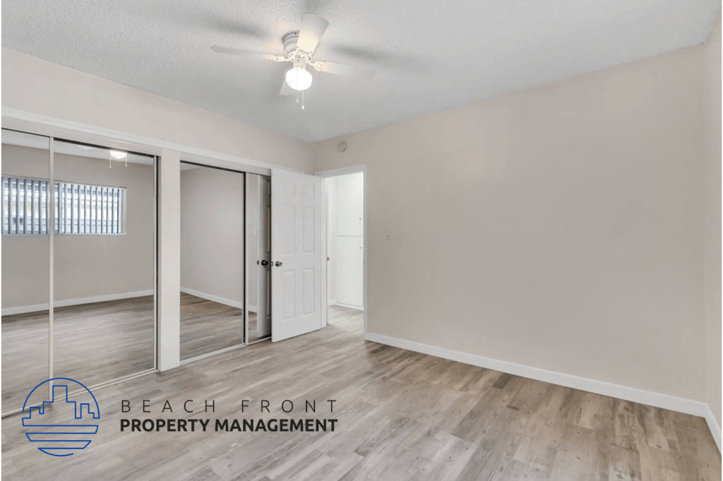a bedroom with a mirrored closet and a ceiling fan