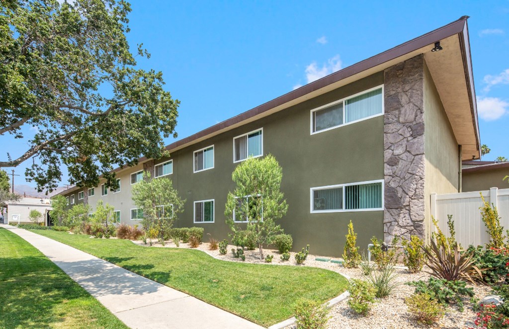 a green house with a sidewalk in front of it