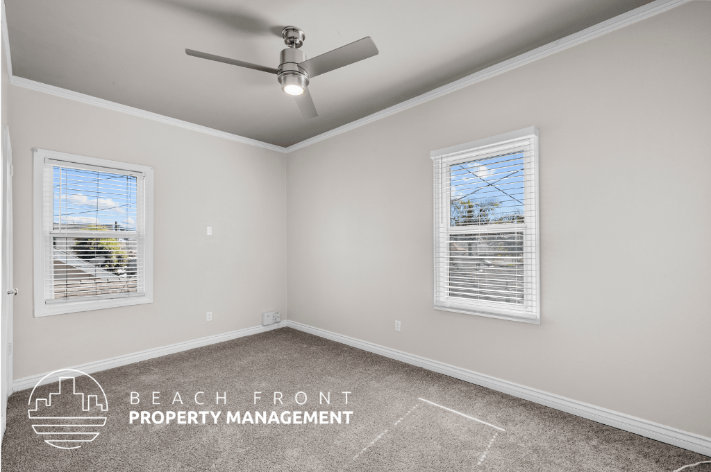 a bedroom with a ceiling fan and two windows
