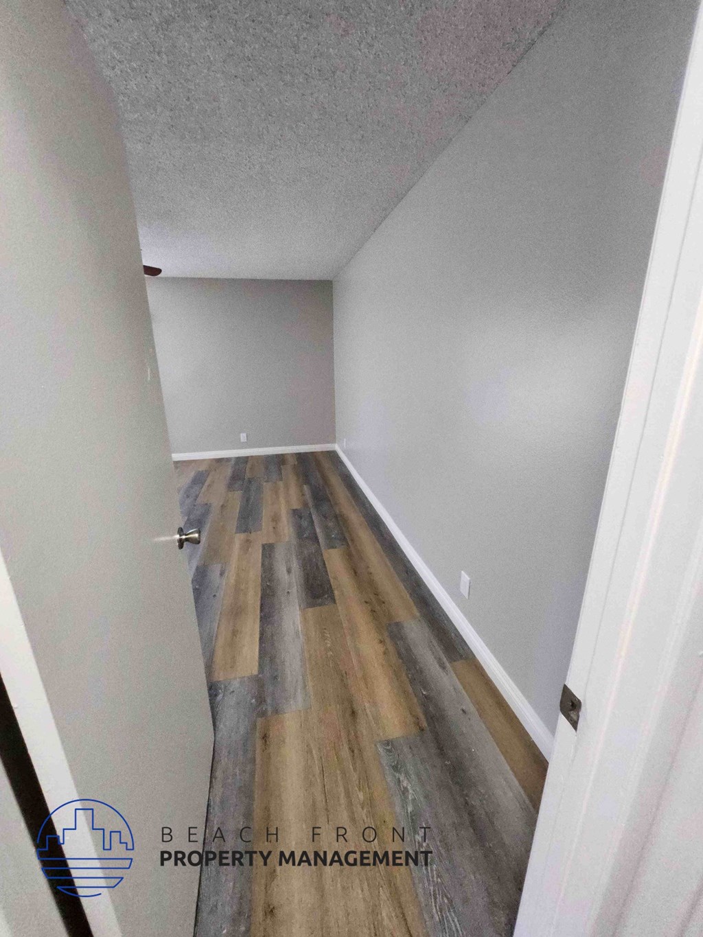 A hallway with wooden flooring and white walls.