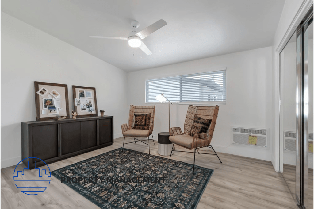 a living room with two chairs and a rug and a ceiling fan