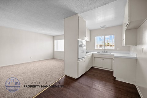 a kitchen with white cabinets and white appliances and a wood floor