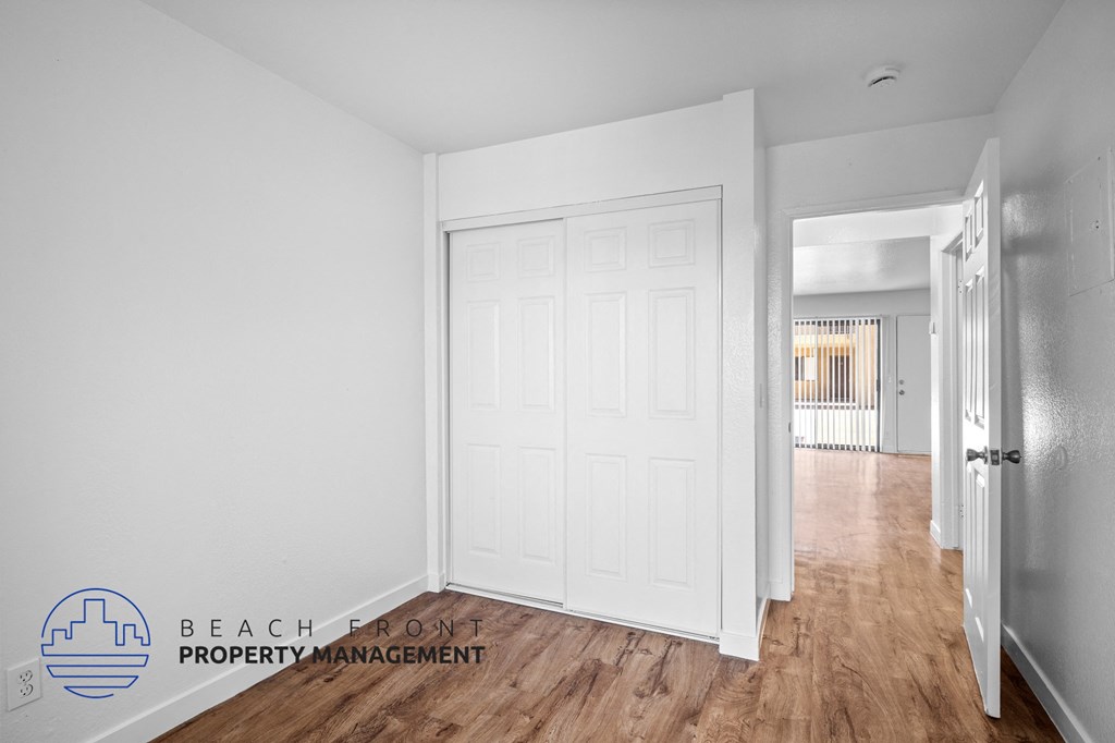 a bedroom with a white door and a hallway with a wood floor
