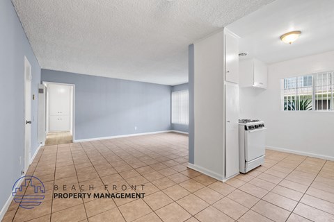 A spacious room with a refrigerator and a window with blinds.