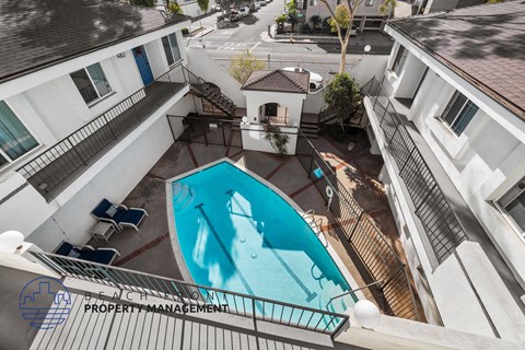 A pool surrounded by apartment buildings with a sign for beach property management.