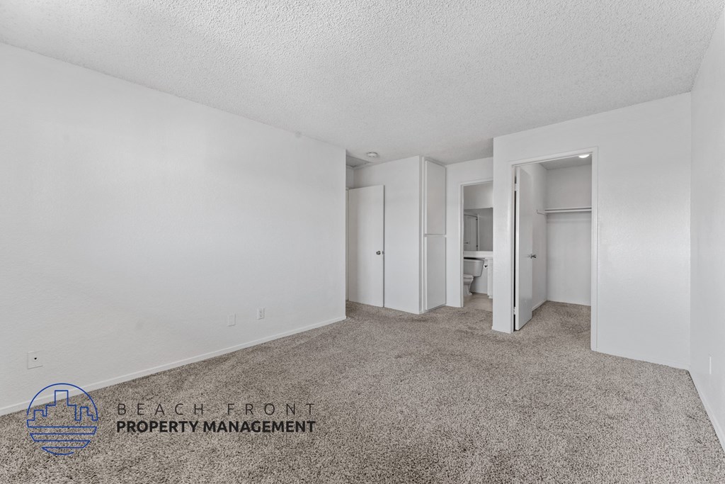 A sparsely furnished room with a carpeted floor and white walls.