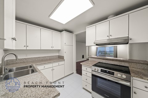 A kitchen with a stove, sink, and cabinets.