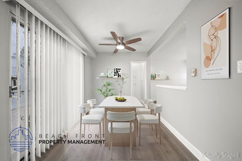 A dining room with a table set for six with a plant on the table and a framed picture on the wall.