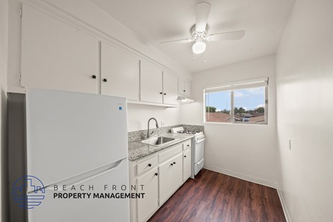 A kitchen with white cabinets and a window overlooking the beach.