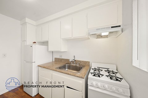 A kitchen with a white stove and white cabinets.