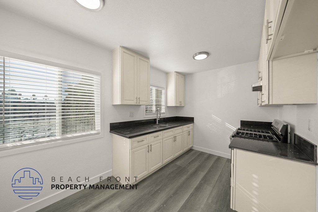 A kitchen with white cabinets and a black countertop.