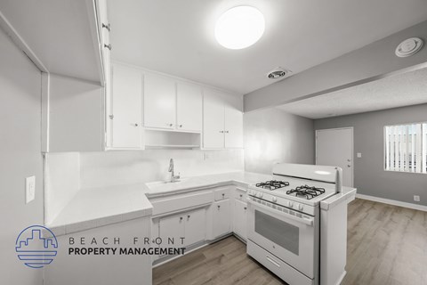 A kitchen with white cabinets and a stove top oven.