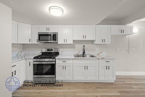 A kitchen with white cabinets and a stove top oven.