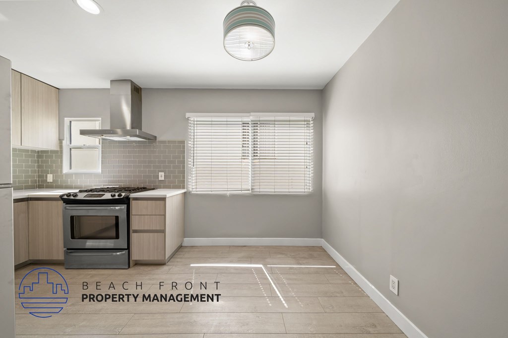 A kitchen with a stove top oven and a hood above it.