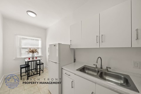 A kitchen with a sink, refrigerator, and a window with a table and chairs.