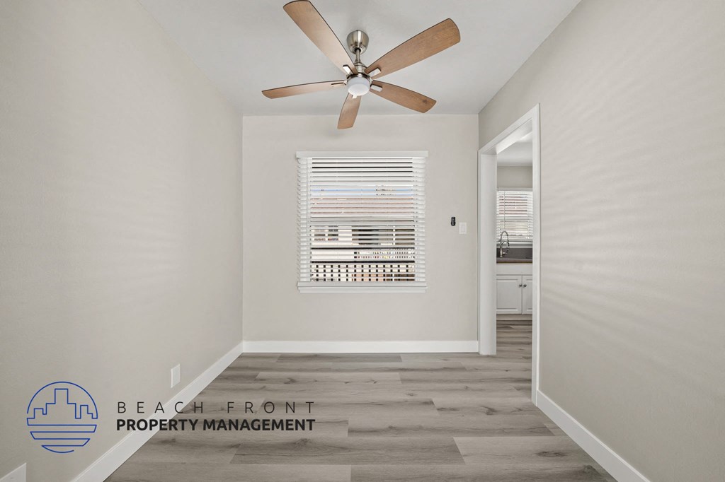 A room with a ceiling fan and a window with blinds.