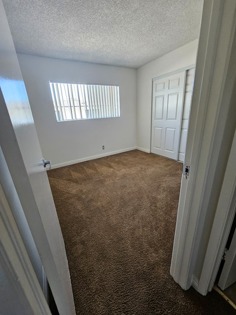 an empty bedroom with a carpeted floor and a window