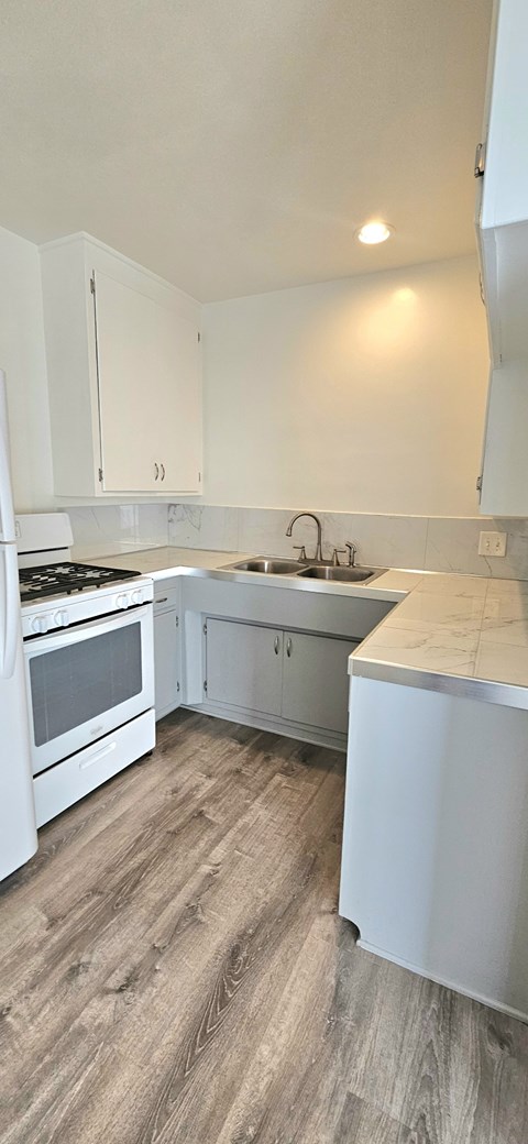 A kitchen with white cabinets and a wooden floor.