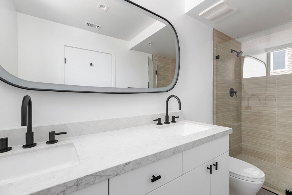 a bathroom with a large mirror above a sink and a toilet