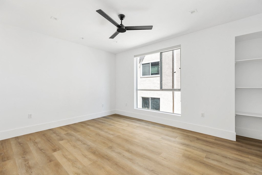 a living room with white walls and a window and a ceiling fan